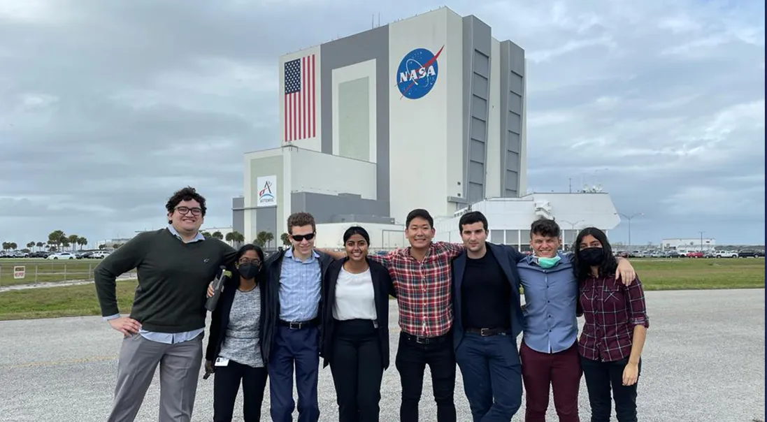 Columbia Student Payload Opportunity with Citizen Science (SPOCS) students standing in front of the NASA Vehicle Assembly Building (VAB)