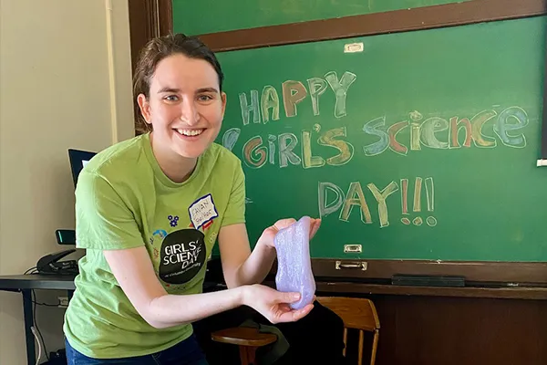 Eavan Donovan is pictured in front of a chalkboard that reads "Happy Girls Science Day" 