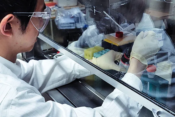 student performs research under lab hood